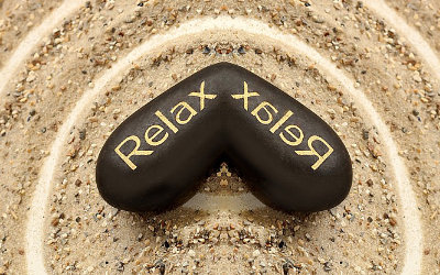 stein im sand mit der aufschrift RELAX - alexander-technik-mg
